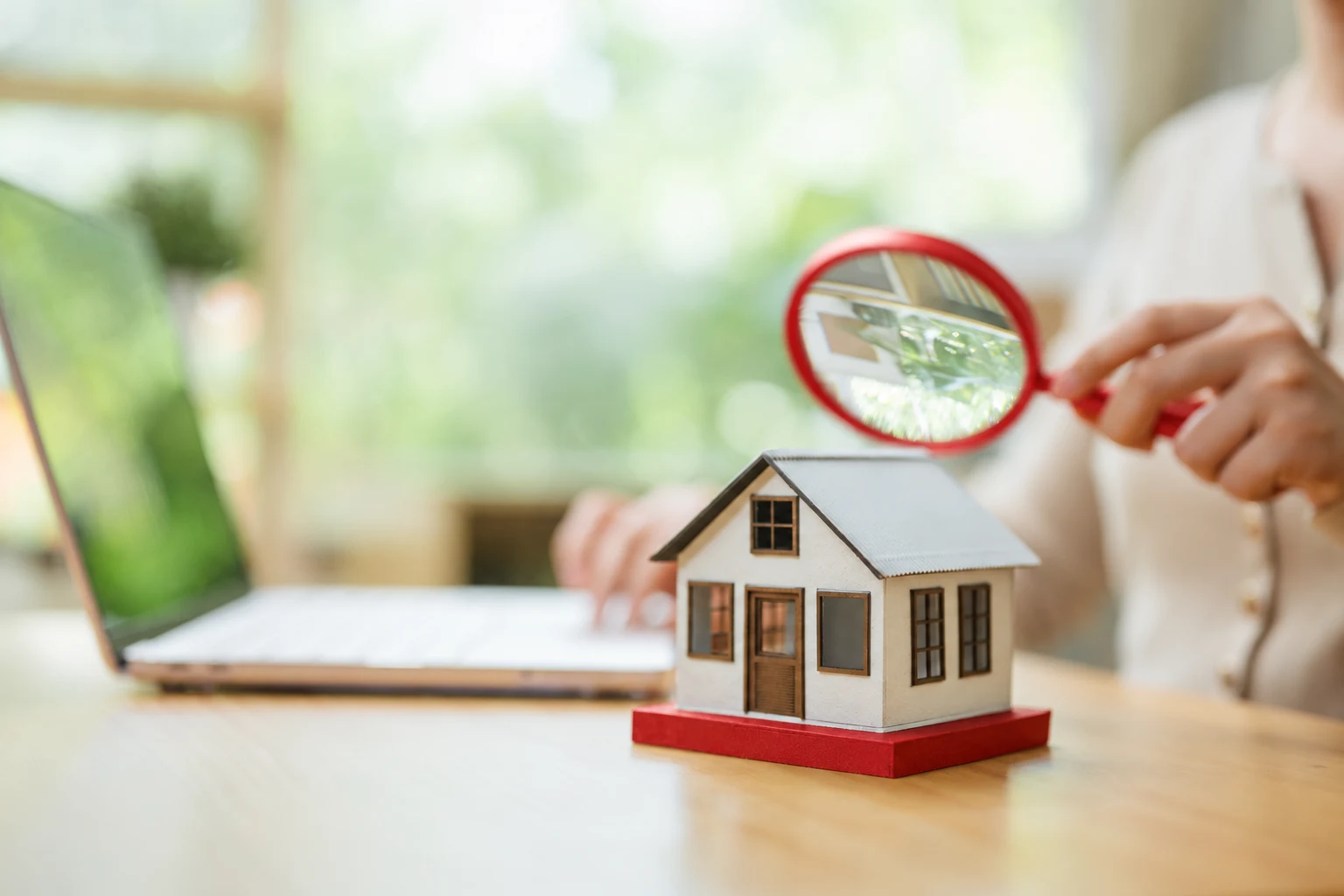 Revisión de las finanzas del hogar, con una lupa roja y una casa en miniatura
